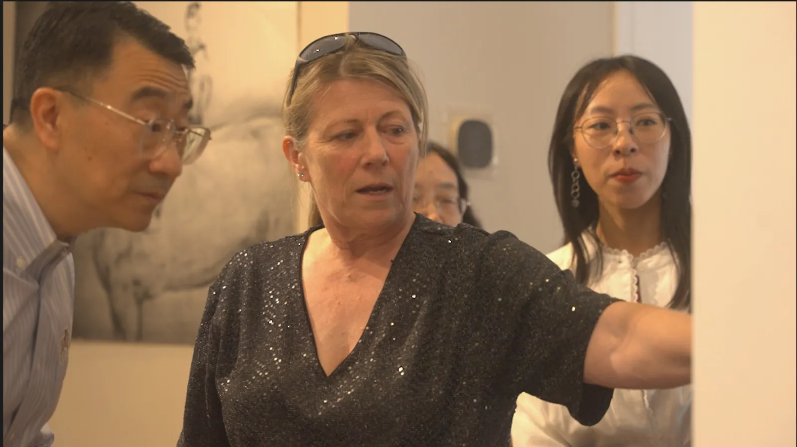 An artist discussing works with guests in the gallery
