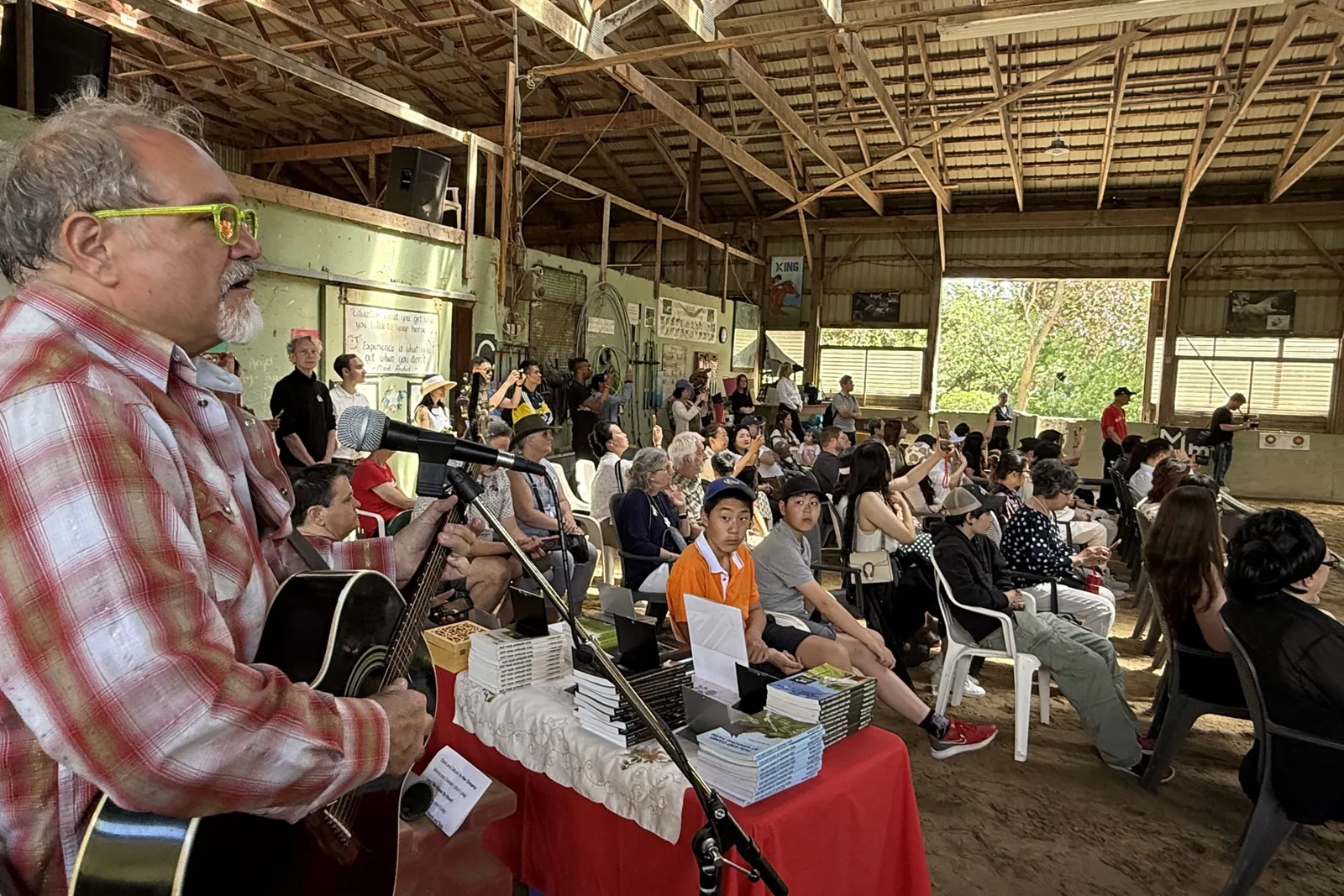 A musician performing before a seated audience in the barn