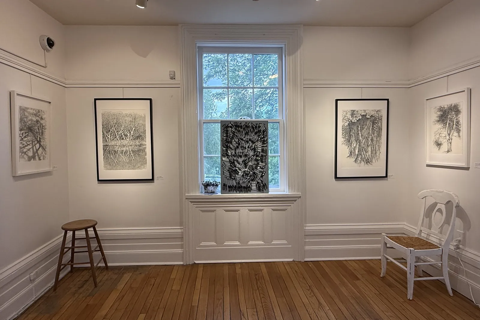 Installation view with framed ink drawings and an artwork in the window