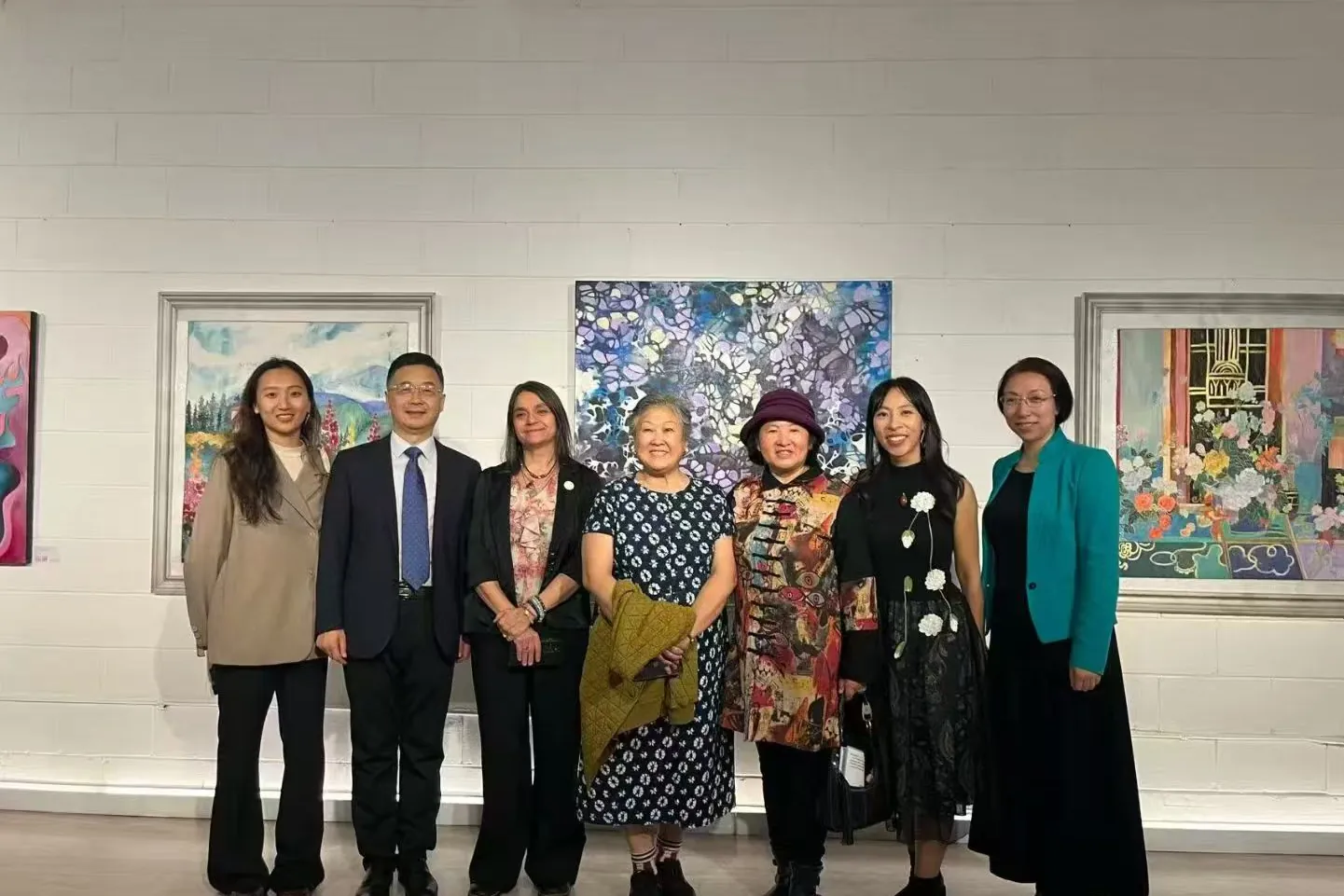 Guests posing in front of paintings in the exhibition